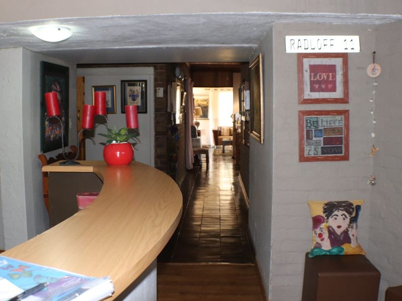 Entrance area featuring a reception counter, hardwood flooring, and exposed brick wall leading into a hallway.