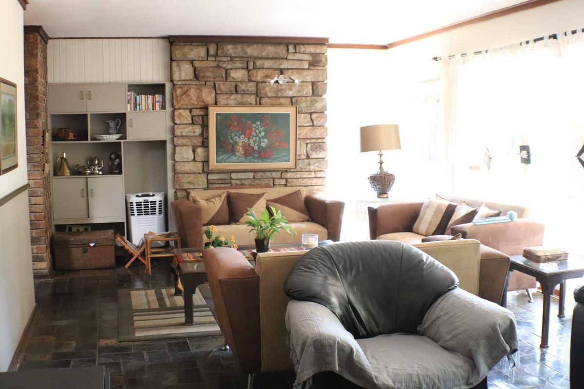 A living room featuring a prominent stone fireplace, built-in storage cabinetry, and dark tiled flooring, offering a traditional aesthetic.