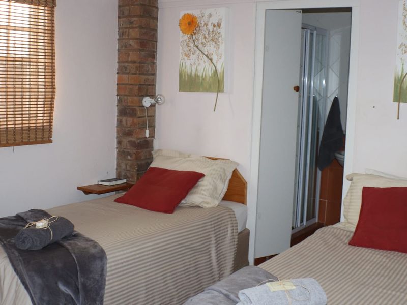 A bedroom featuring an exposed brick pillar, bamboo window blinds, and direct access to an en-suite bathroom.