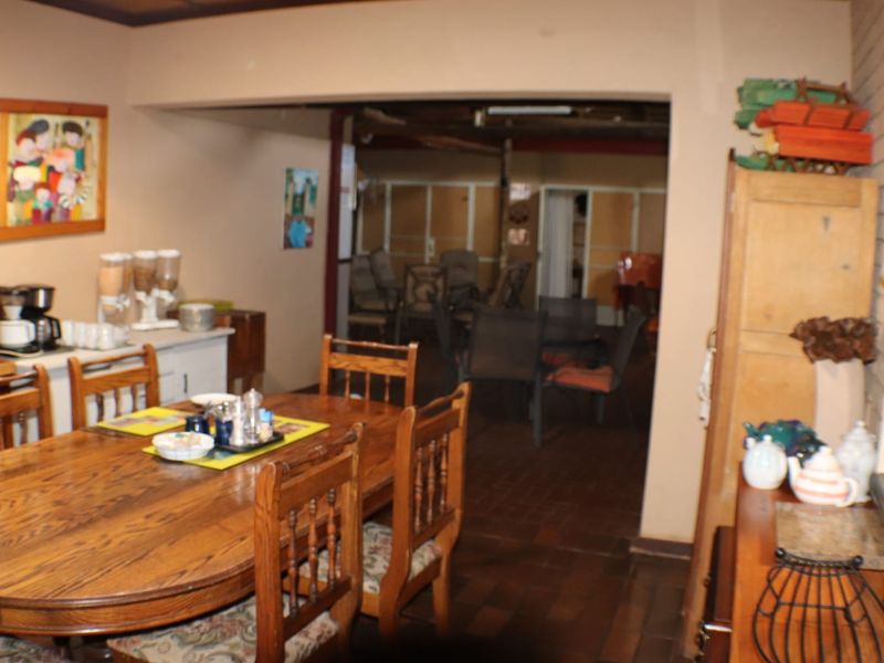 Open plan dining and living area featuring exposed ceiling beams, brick wall accents, and tiled flooring in a commercial property setting.