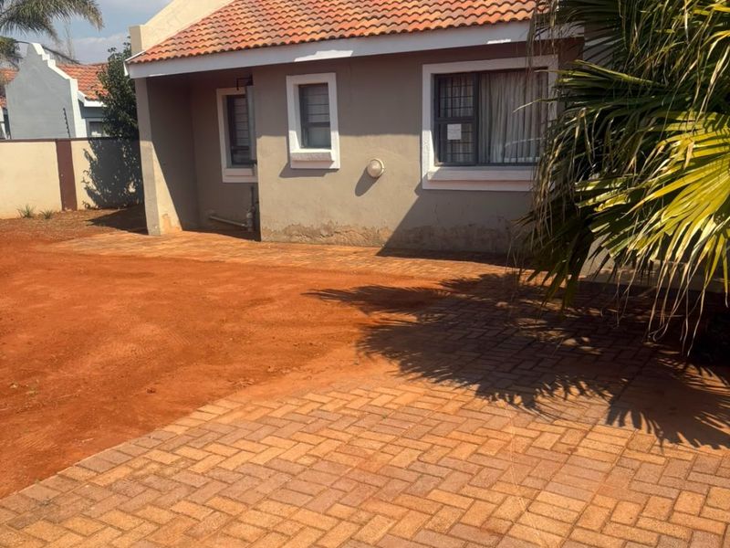 Rear exterior view of the house featuring a paved driveway, terracotta tiled roof, and boundary walling.