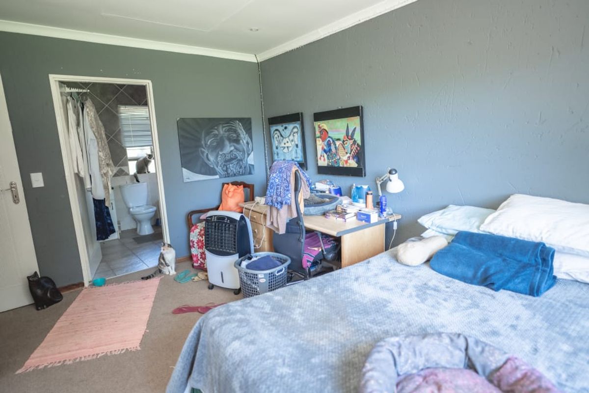 A bedroom featuring an attached en-suite bathroom with tiled flooring and neutral wall finishes, offering a functional layout with carpeted flooring.