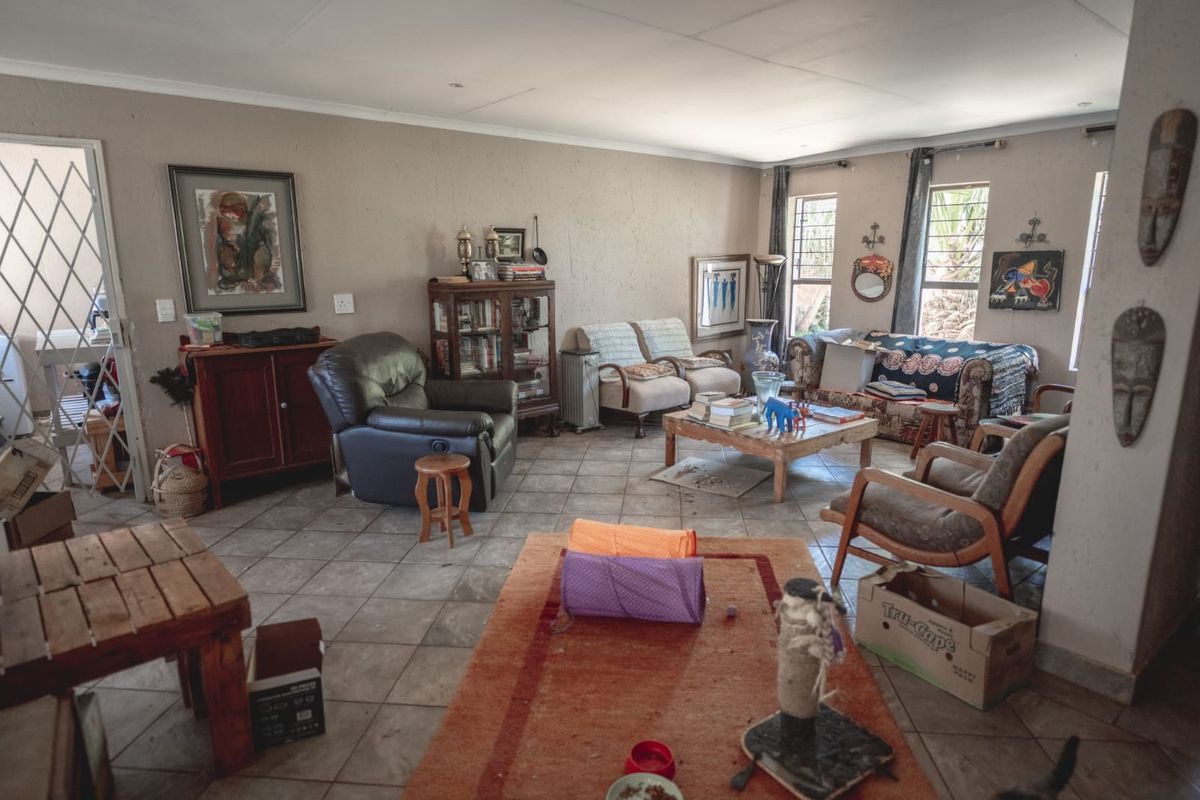 A spacious living room featuring tiled flooring and natural light through windows with security bars, offering a versatile layout for comfortable family living.