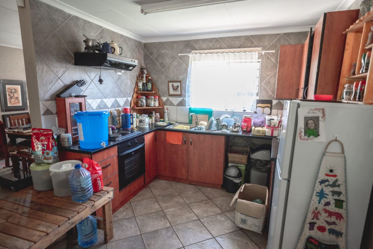 A functional kitchen featuring wooden cabinetry, tiled backsplash, built-in oven and hob, and tiled flooring, offering a practical layout for daily meal preparation.