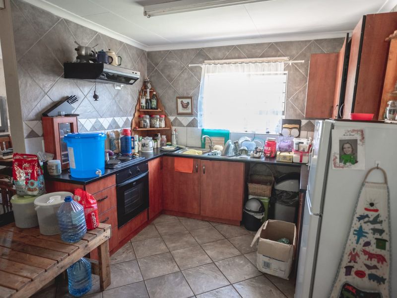 A functional kitchen featuring wooden cabinetry, tiled backsplash, built-in oven and hob, and tiled flooring, offering a practical layout for daily meal preparation.