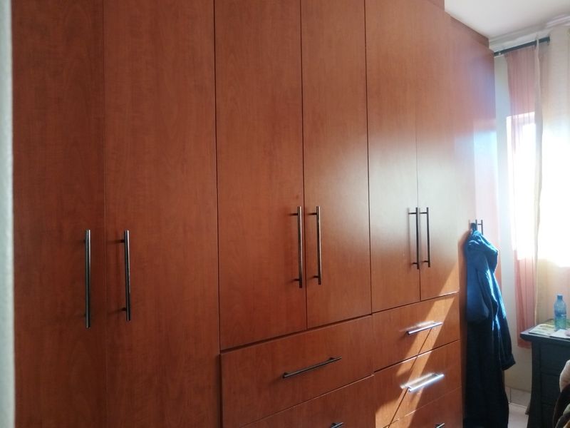 A bedroom featuring extensive floor-to-ceiling built-in wooden cabinetry with modern metal handles, providing ample integrated storage space.