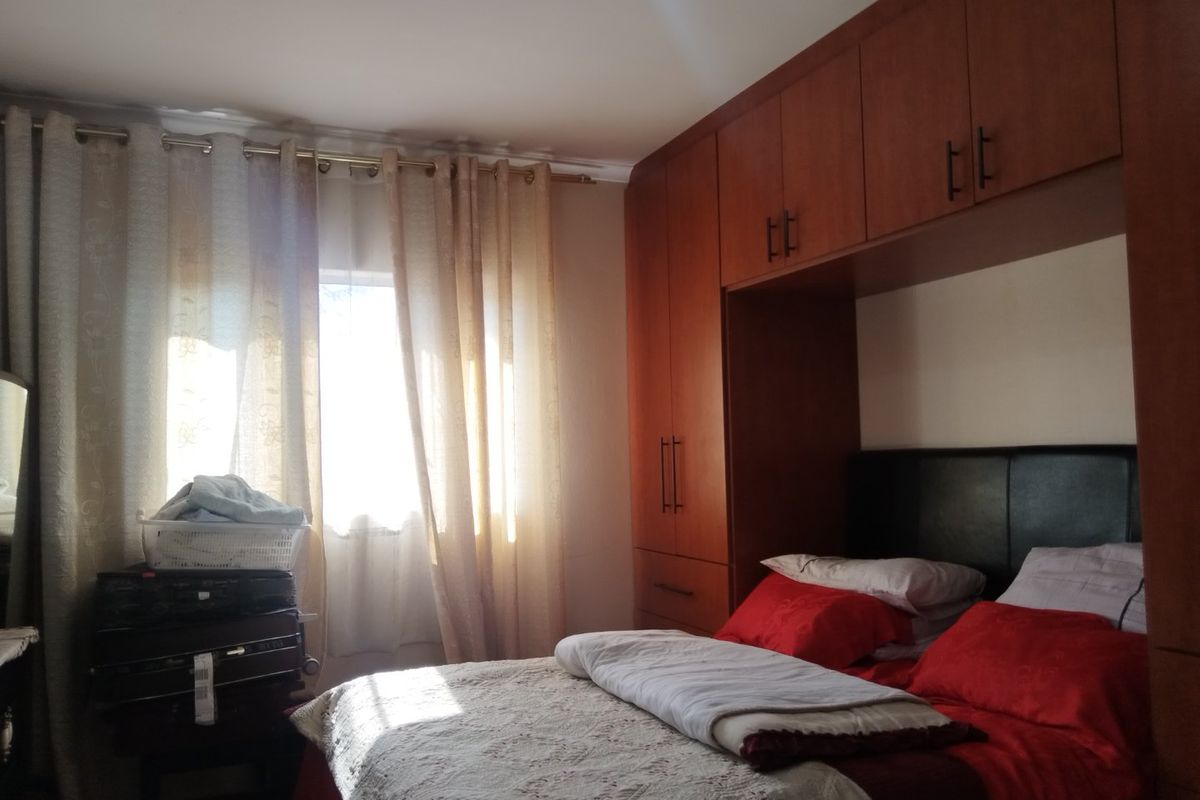 A bedroom featuring extensive built-in wooden cupboards and overhead storage cabinetry, providing ample storage space.