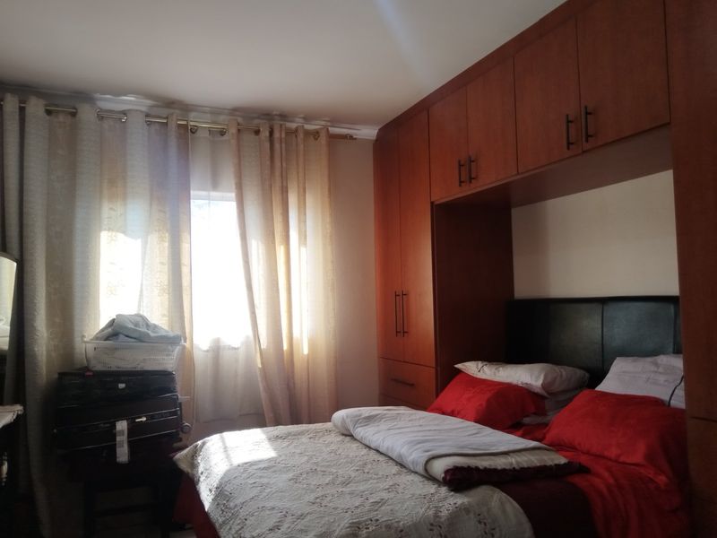 A bedroom featuring extensive built-in wooden cupboards and overhead storage cabinetry, providing ample storage space.