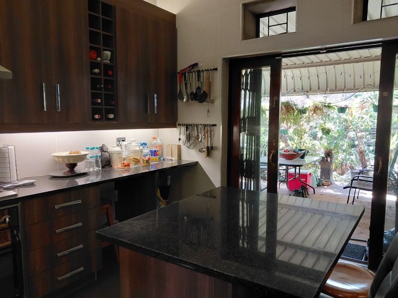Modern kitchen featuring dark wood cabinetry, granite countertops, and a central island, with direct access to an outdoor patio area.