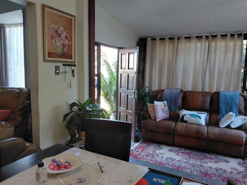 A comfortable living room area featuring tiled flooring and direct access to the exterior through a timber door.