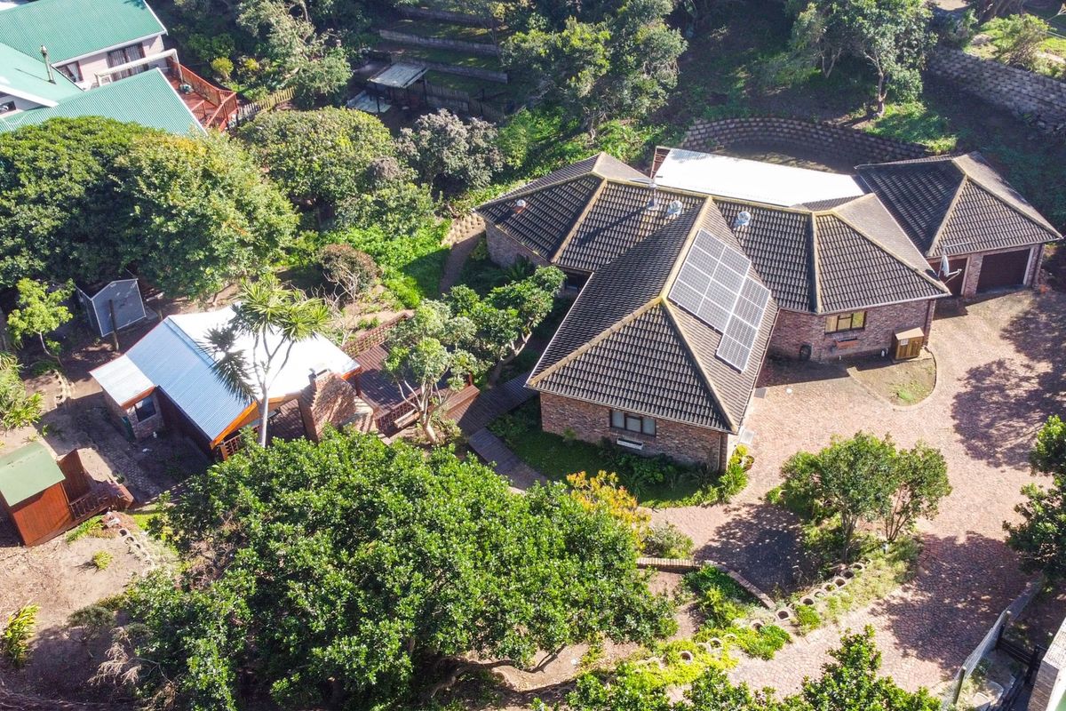 Aerial view of a brick house featuring a tiled roof with solar panels, a paved driveway, and established garden surroundings.