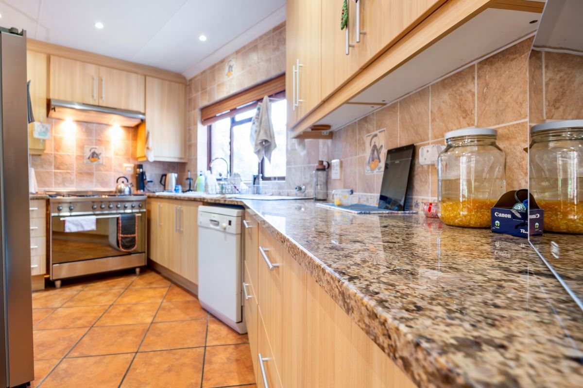 A functional kitchen featuring light wood cabinetry, granite countertops, tiled backsplash, and a built-in gas stove with an extractor fan.