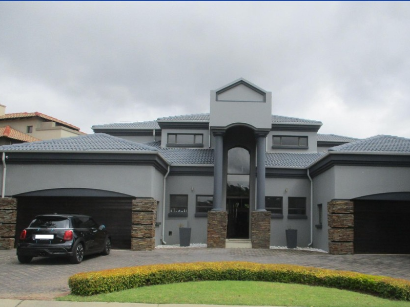Modern double-story residence featuring a paved driveway, double garage, and a striking entrance with stone cladding and architectural columns.