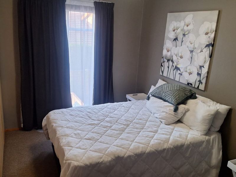 A cozy bedroom featuring neutral wall tones, carpeted flooring, and a functional built-in wardrobe with ample storage space.
