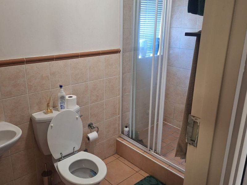 A functional bathroom featuring a pedestal basin, toilet, and a separate shower enclosure with tiled finishes throughout.