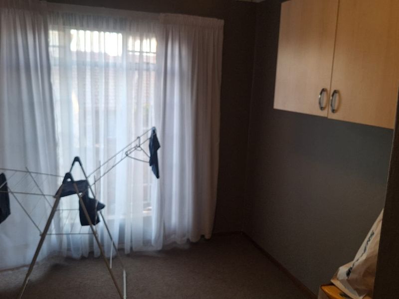 A functional laundry area featuring wall-mounted storage cabinetry and a window with curtains.