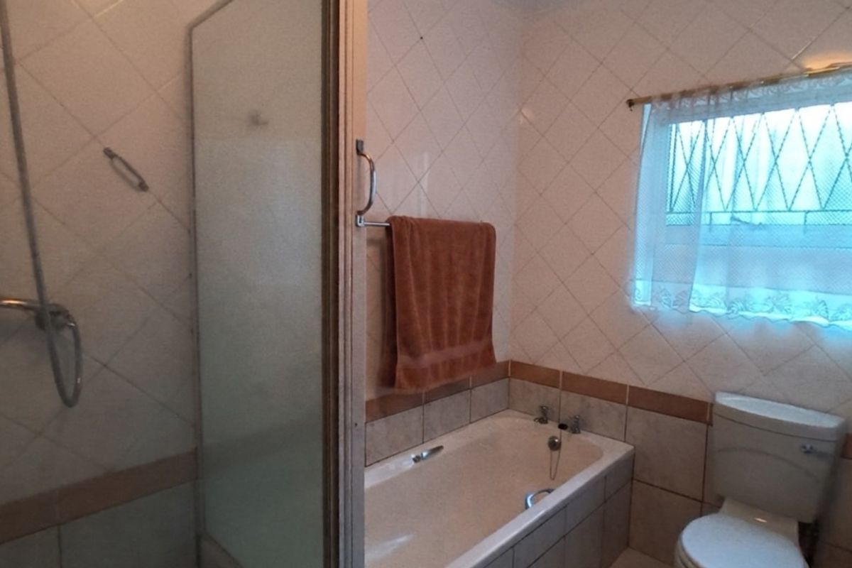 A functional bathroom featuring a combined shower and bathtub, toilet, and tiled wall finishes.