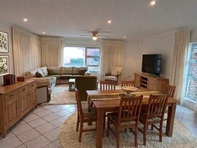 Spacious open-plan living and dining area featuring ceramic floor tiles, recessed downlighting, and a ceiling fan, creating a comfortable and functional family space.