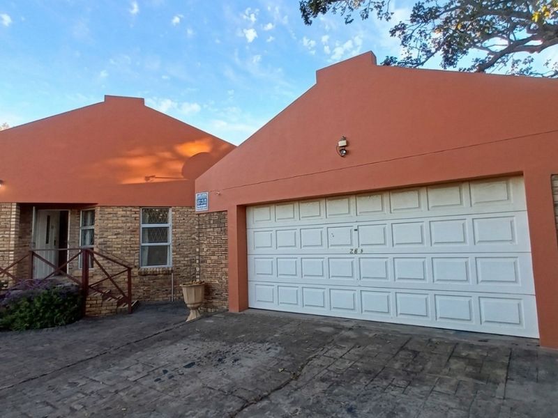 Front exterior view of the house featuring a brick and stucco facade, a paved driveway, and a white sectional garage door.