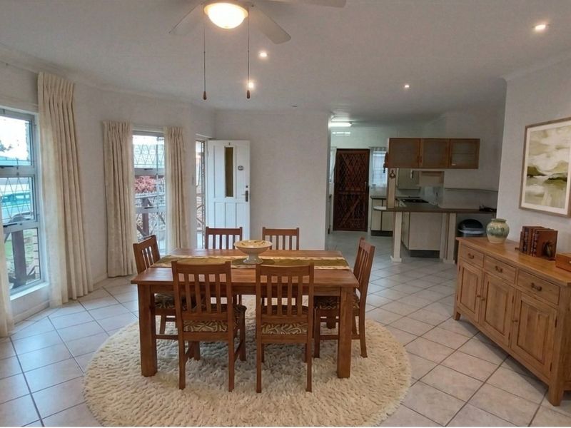 Open-plan living and dining area featuring tiled flooring, recessed lighting, and a functional kitchen with breakfast counter and ample cabinetry.