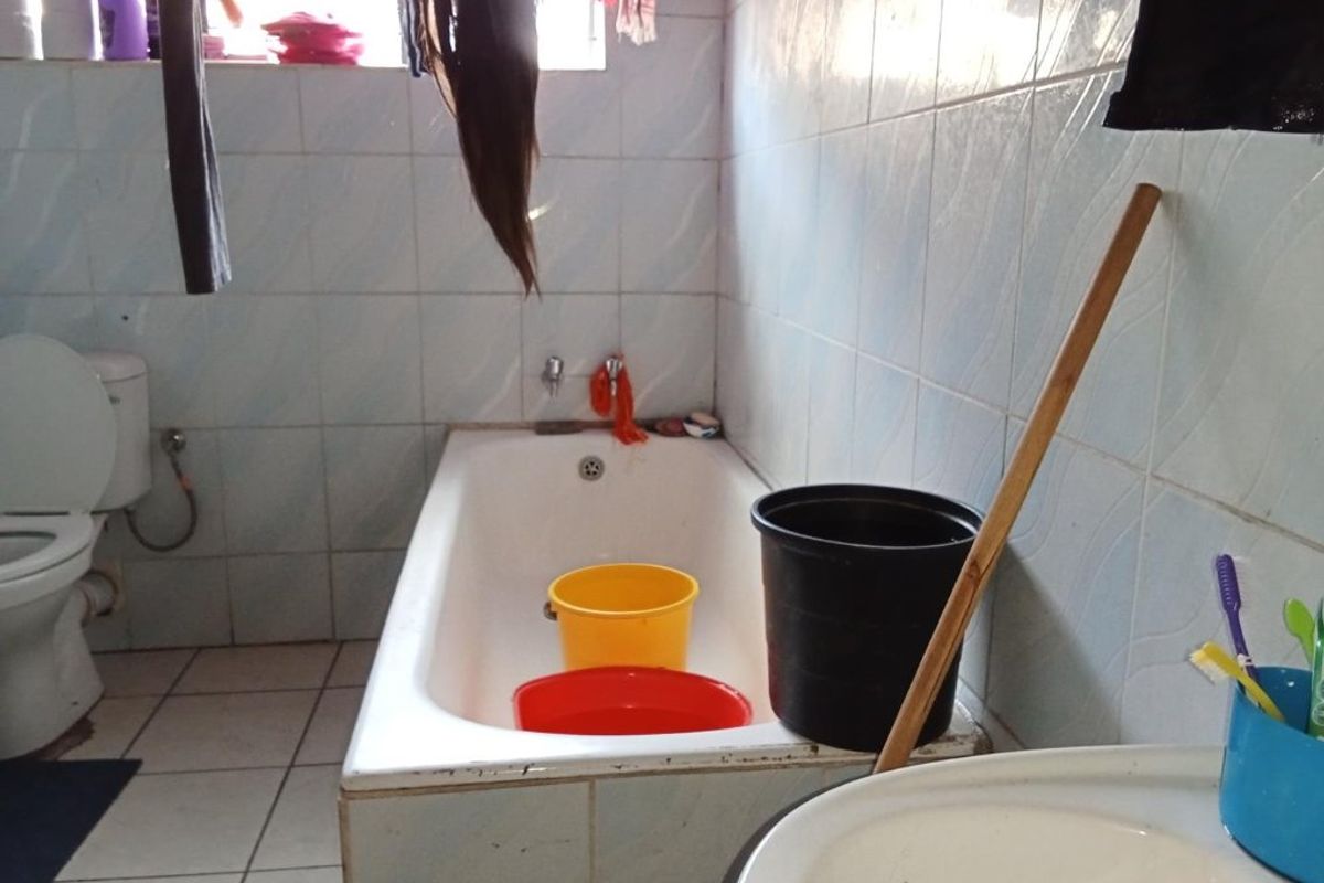 A functional bathroom featuring a standard bathtub, toilet, and washbasin with tiled wall finishes, requiring cosmetic updates to improve its overall condition.