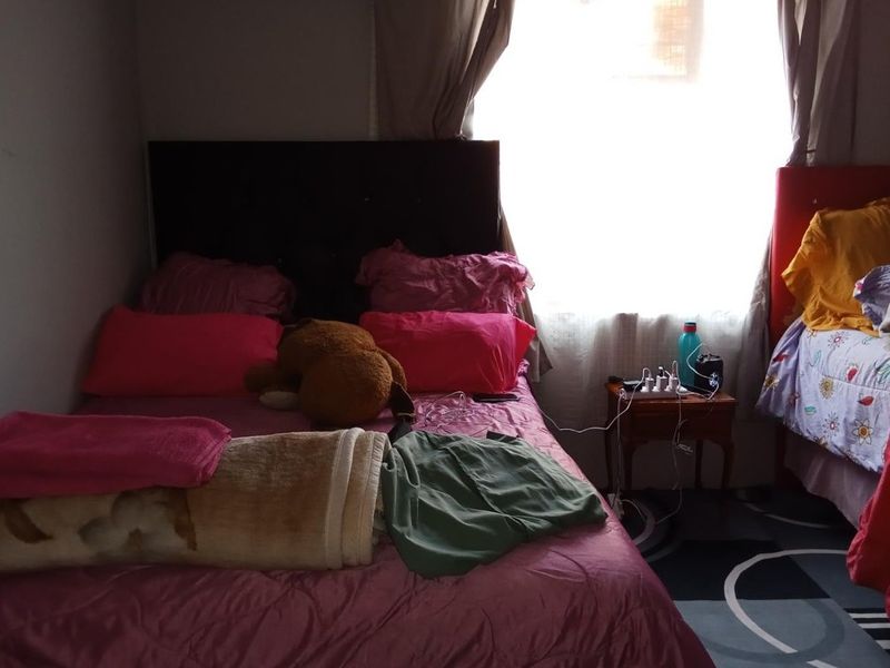 A bedroom featuring a window with curtains and space for multiple beds.
