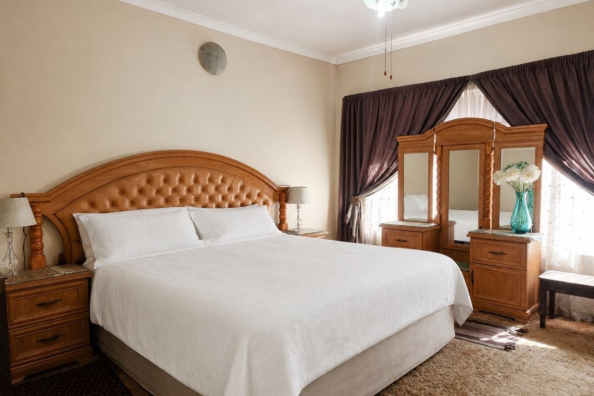 A spacious bedroom featuring neutral wall tones, coving, and a ceiling fan, offering a comfortable and well-maintained living space.