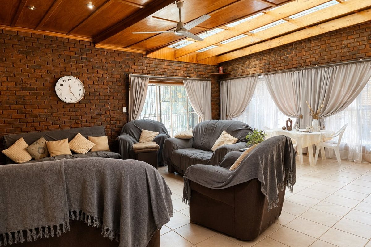 Spacious living area featuring exposed brick walls, a timber panelled ceiling with skylights, ceiling fan, and tiled flooring with access to the outdoors.