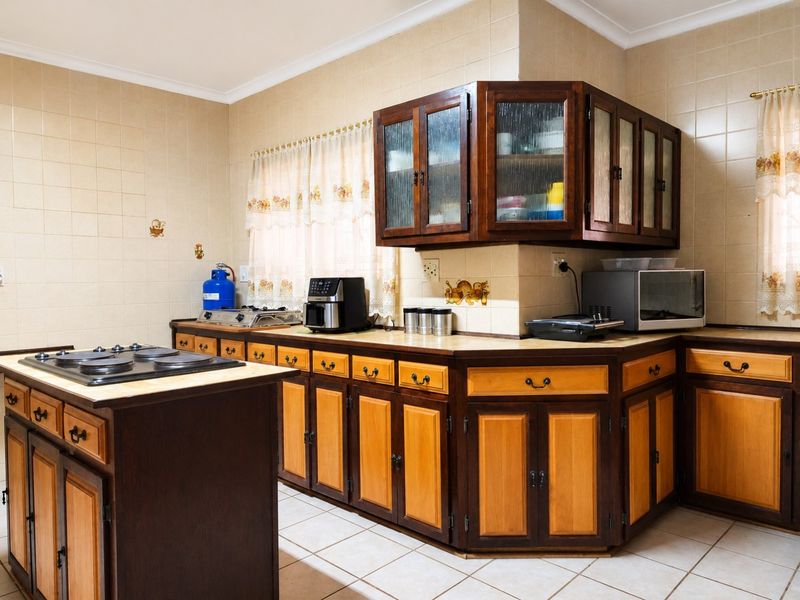 A traditional kitchen featuring two-tone wooden cabinetry, tiled splashbacks, and a central island with a built-in gas hob.