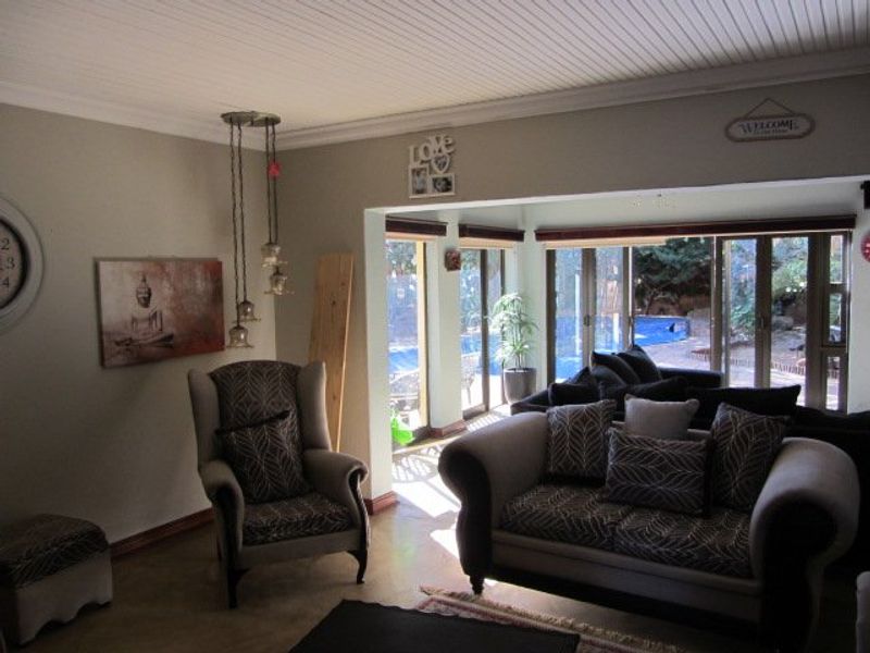 Spacious living area featuring a beadboard ceiling, concrete flooring, and large sliding glass doors providing direct access to the outdoor pool area.