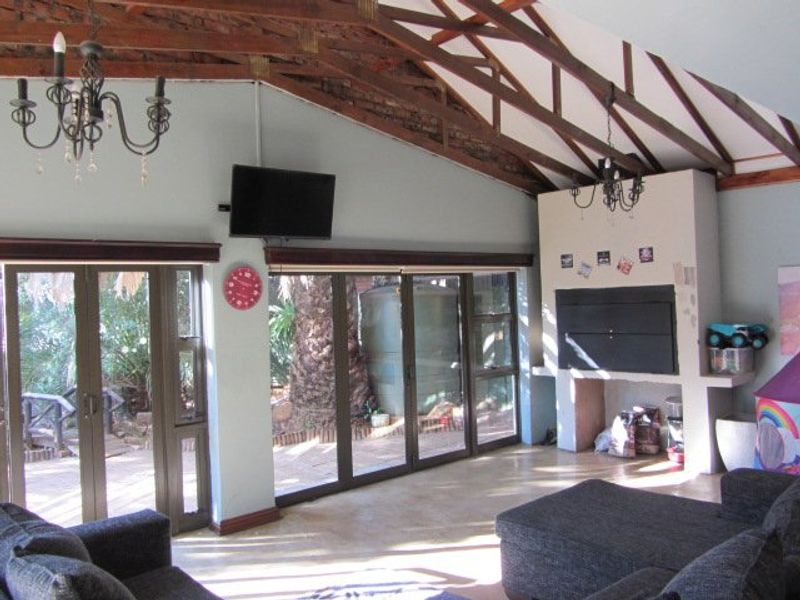 Spacious living room featuring exposed timber roof trusses, a built-in fireplace, and large aluminium sliding doors providing direct access to the outdoor patio area.