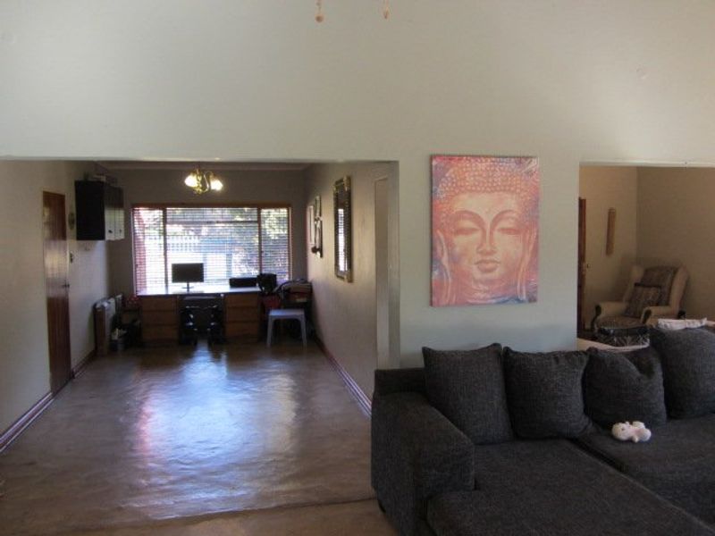 Open plan living area featuring vaulted ceilings, polished concrete flooring, and large windows providing natural light.