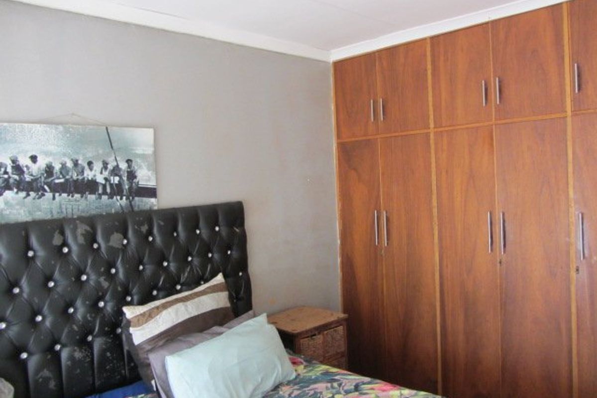 A bedroom featuring floor-to-ceiling built-in wooden cupboards and a tufted headboard.