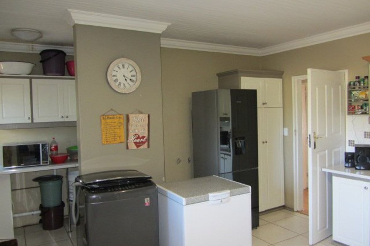 A functional kitchen area featuring built-in cabinetry, tiled flooring, and a panelled ceiling, providing a practical layout for daily food preparation and storage.