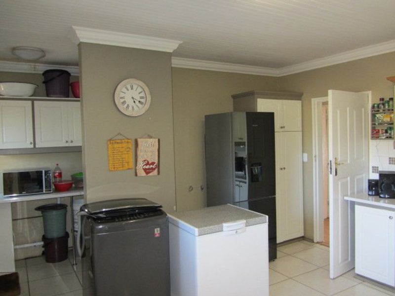 A functional kitchen area featuring built-in cabinetry, tiled flooring, and a panelled ceiling, providing a practical layout for daily food preparation and storage.
