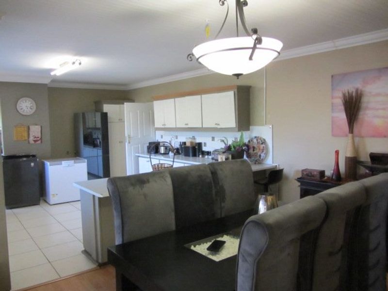 Open plan kitchen and dining area featuring tiled flooring, built-in cabinetry, and decorative pendant lighting.