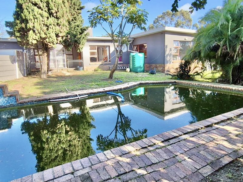 Rear garden area featuring a swimming pool with brick paving and a water tank, requiring significant maintenance and landscaping.