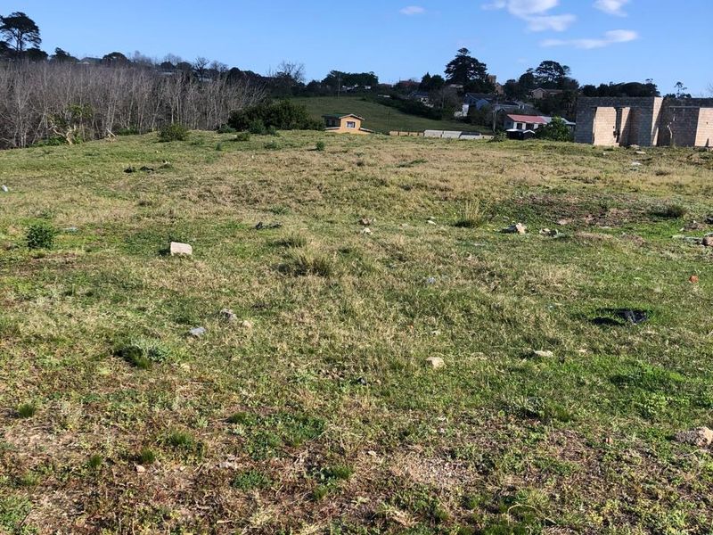 A view of an open, undeveloped residential plot featuring natural grass cover and surrounding neighborhood landscape.