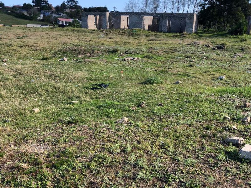 Vacant residential land featuring an incomplete concrete block structure, offering a blank canvas for development in a quiet neighborhood setting.