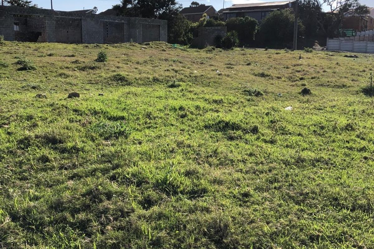 A view of a vacant residential plot featuring grass coverage and surrounding neighborhood infrastructure.