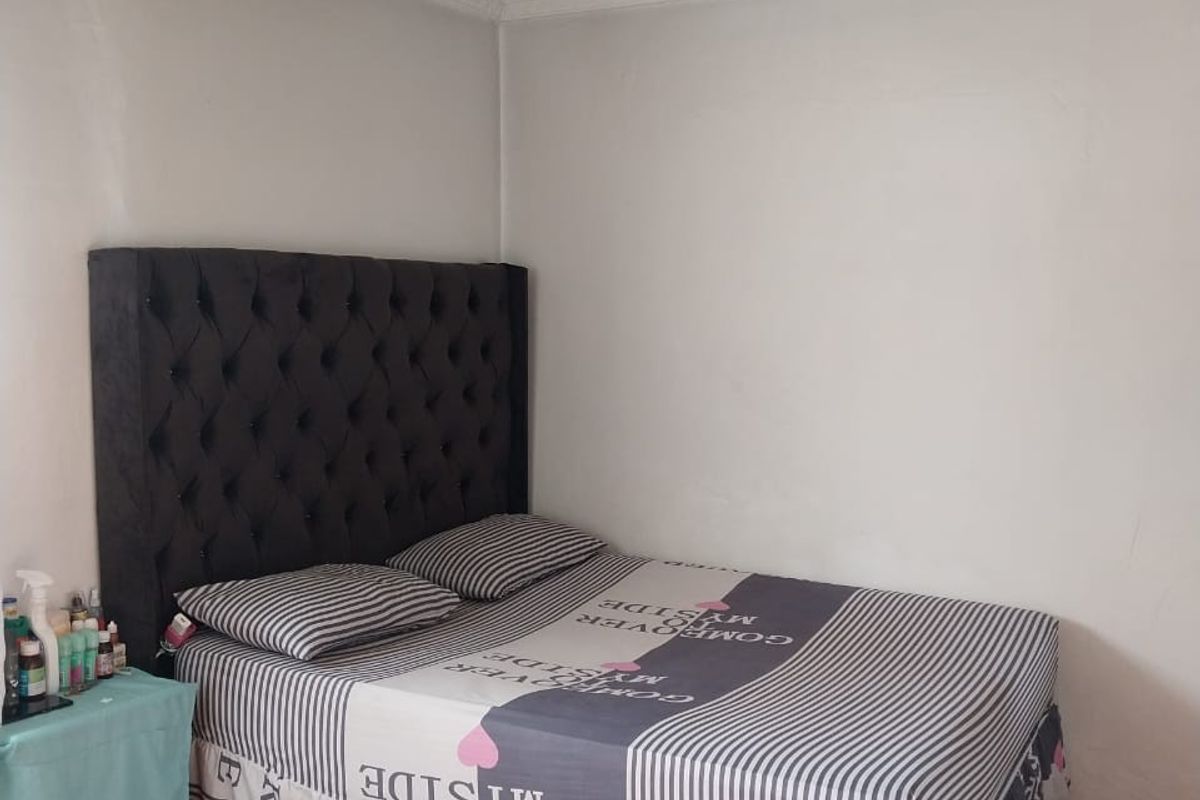 A bedroom featuring tiled flooring and a tongue and groove ceiling with visible signs of wear and aging.