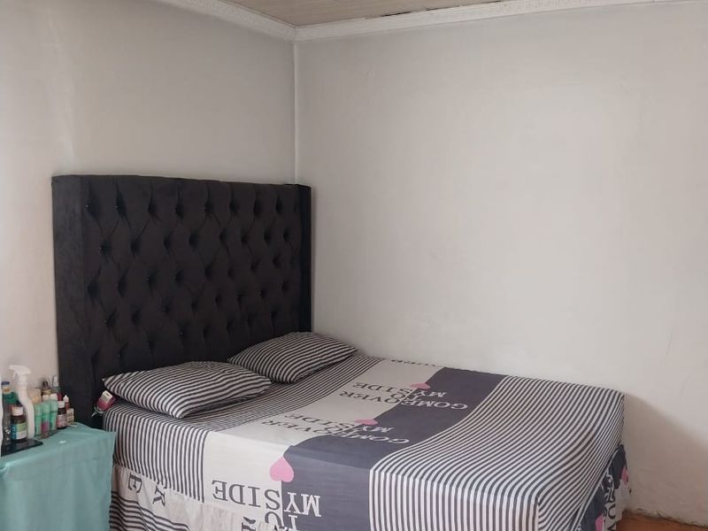 A bedroom featuring tiled flooring and a tongue and groove ceiling with visible signs of wear and aging.