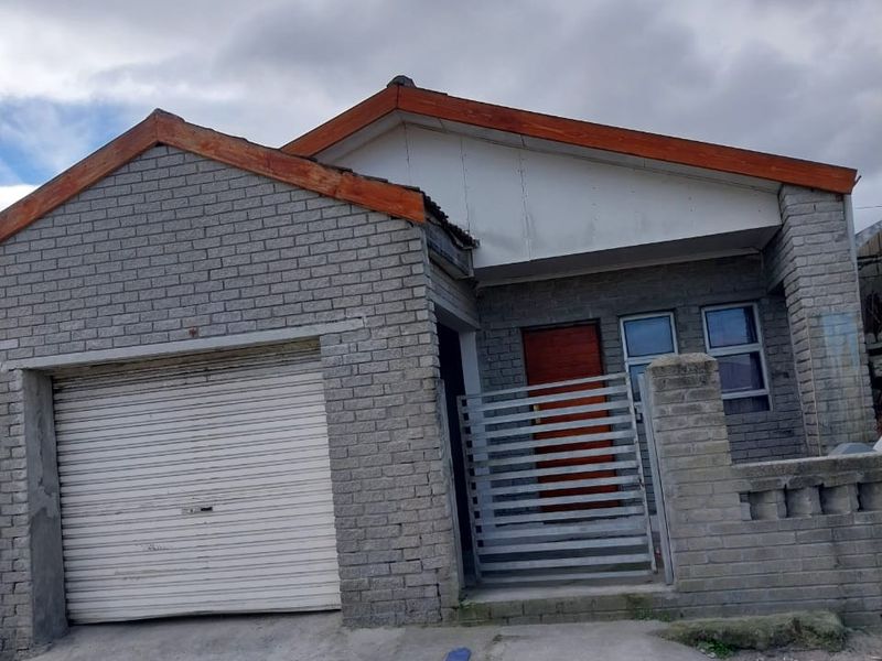 Front elevation of a single-story brick house featuring a roller garage door, metal security gate, and concrete driveway.