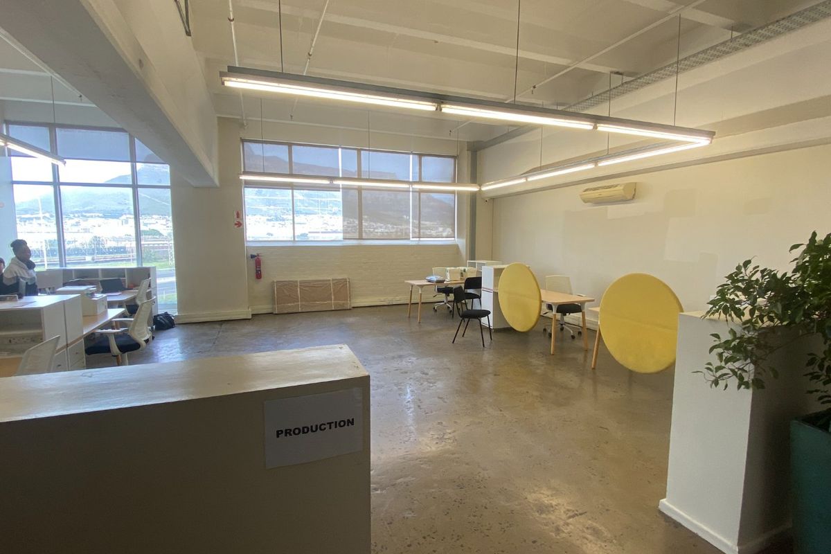 Open-plan commercial office space featuring polished concrete floors, exposed ceilings, large windows with natural light, and integrated air conditioning.