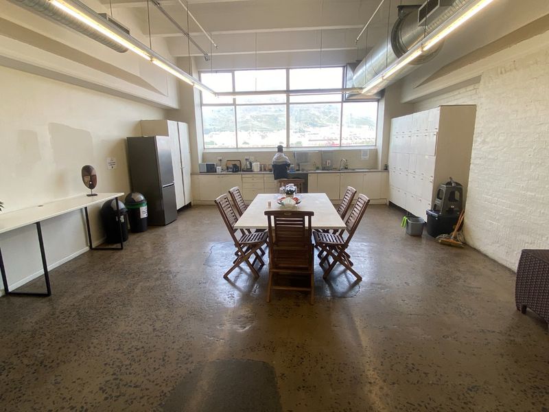 Spacious open-plan commercial kitchen and dining area featuring polished concrete floors, exposed industrial ducting, and ample built-in storage lockers.