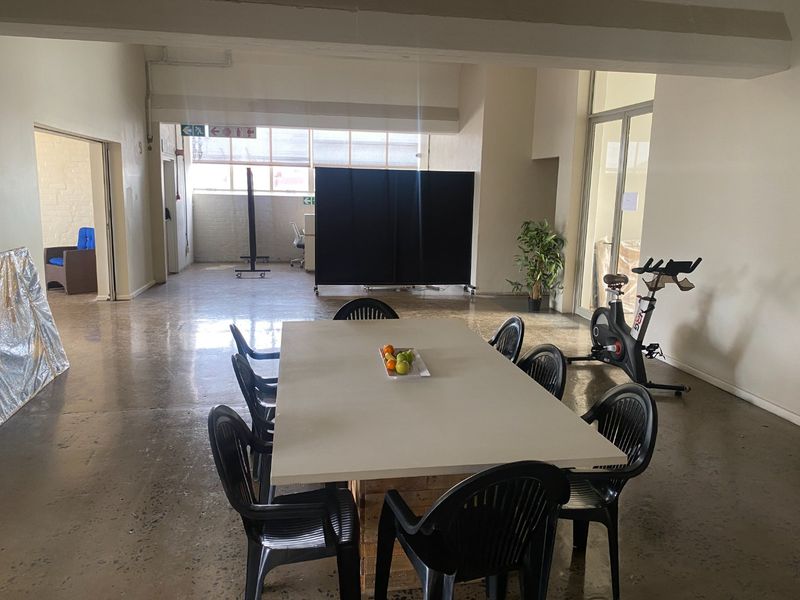 Spacious open-plan commercial area featuring polished concrete floors, exposed structural beams, and large industrial-style windows providing ample natural light.