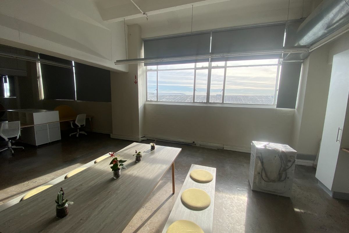 Spacious commercial office area featuring polished concrete floors, exposed industrial ceiling elements, and large windows providing ample natural light.