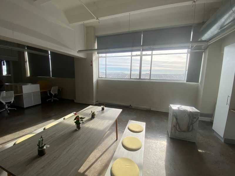 Spacious commercial office area featuring polished concrete floors, exposed industrial ceiling elements, and large windows providing ample natural light.
