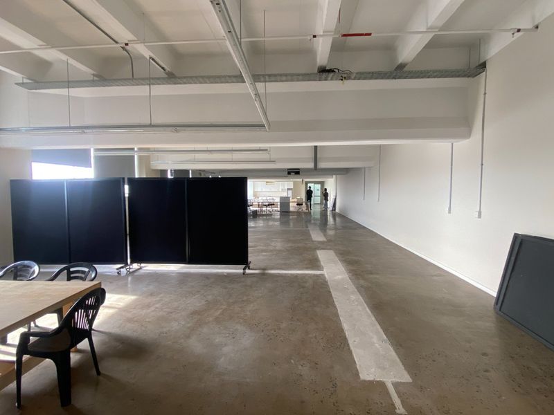 Spacious open-plan commercial office area featuring industrial-style exposed ceilings, polished concrete floors, and integrated fire safety systems.