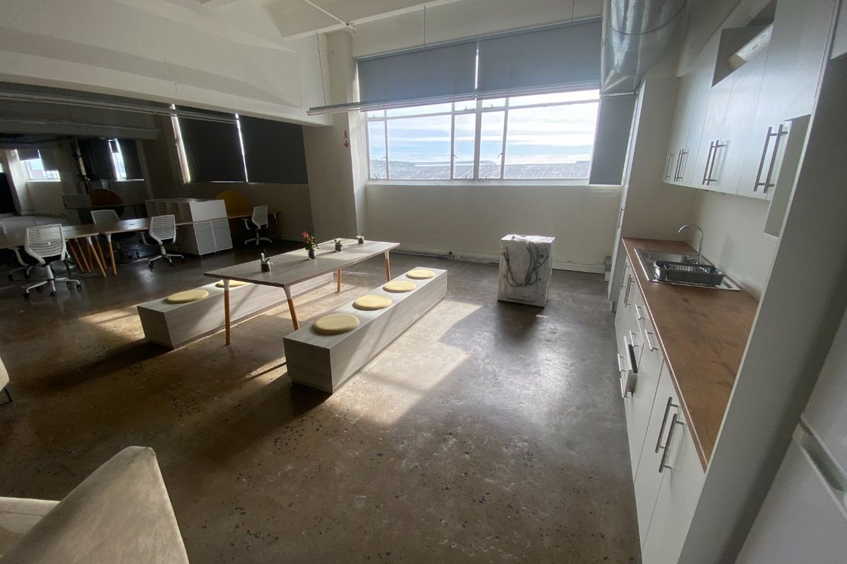 Spacious open-plan commercial office area featuring polished concrete floors, exposed industrial ceiling elements, and a functional kitchenette with modern cabinetry.